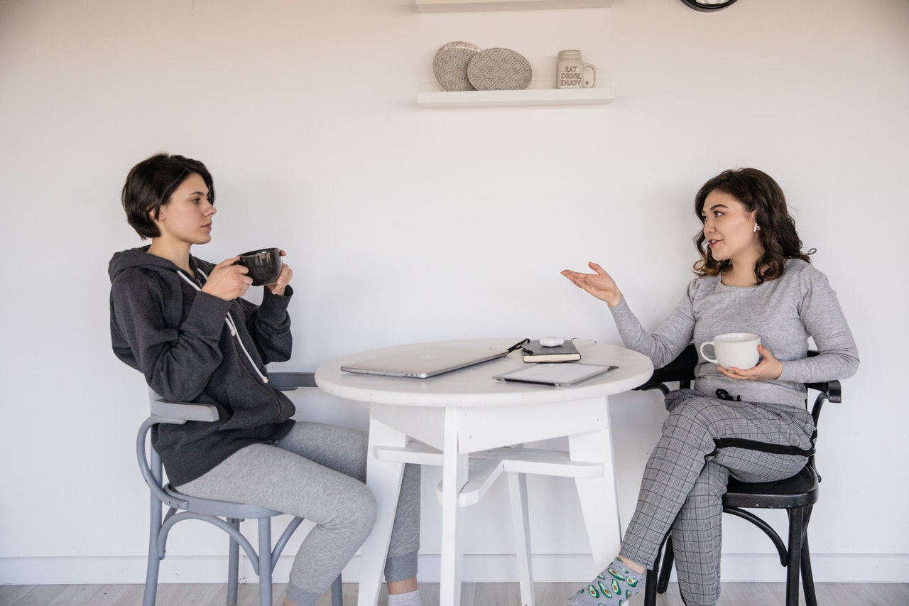 Kobiety rozmawiają za soba przy kawie