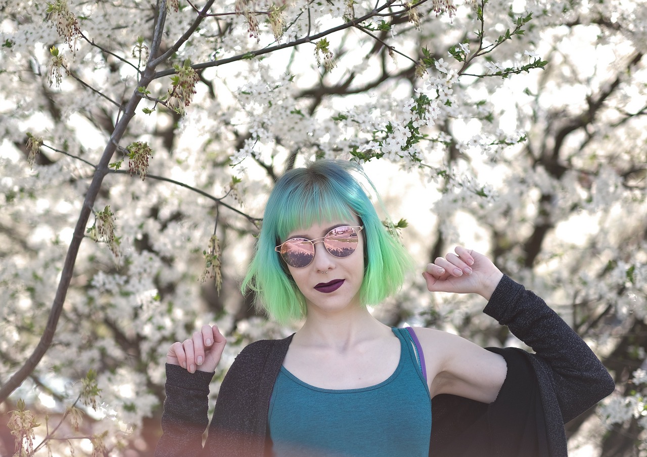 Kobieta z kolorowymi włosami na tle kwitnącego drzewa
