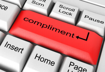 Prezentowany obrazek przedstawia klawiaturę komputera z wyjątkowym przyciskiem o napisie "compliment". Ten estetyczny i inspirujący przycisk jest nie tylko funkcjonalnym elementem klawiatury, ale również symbolem dla wyrażania życzliwości i pozytywnych słów w naszej codziennej interakcji online.