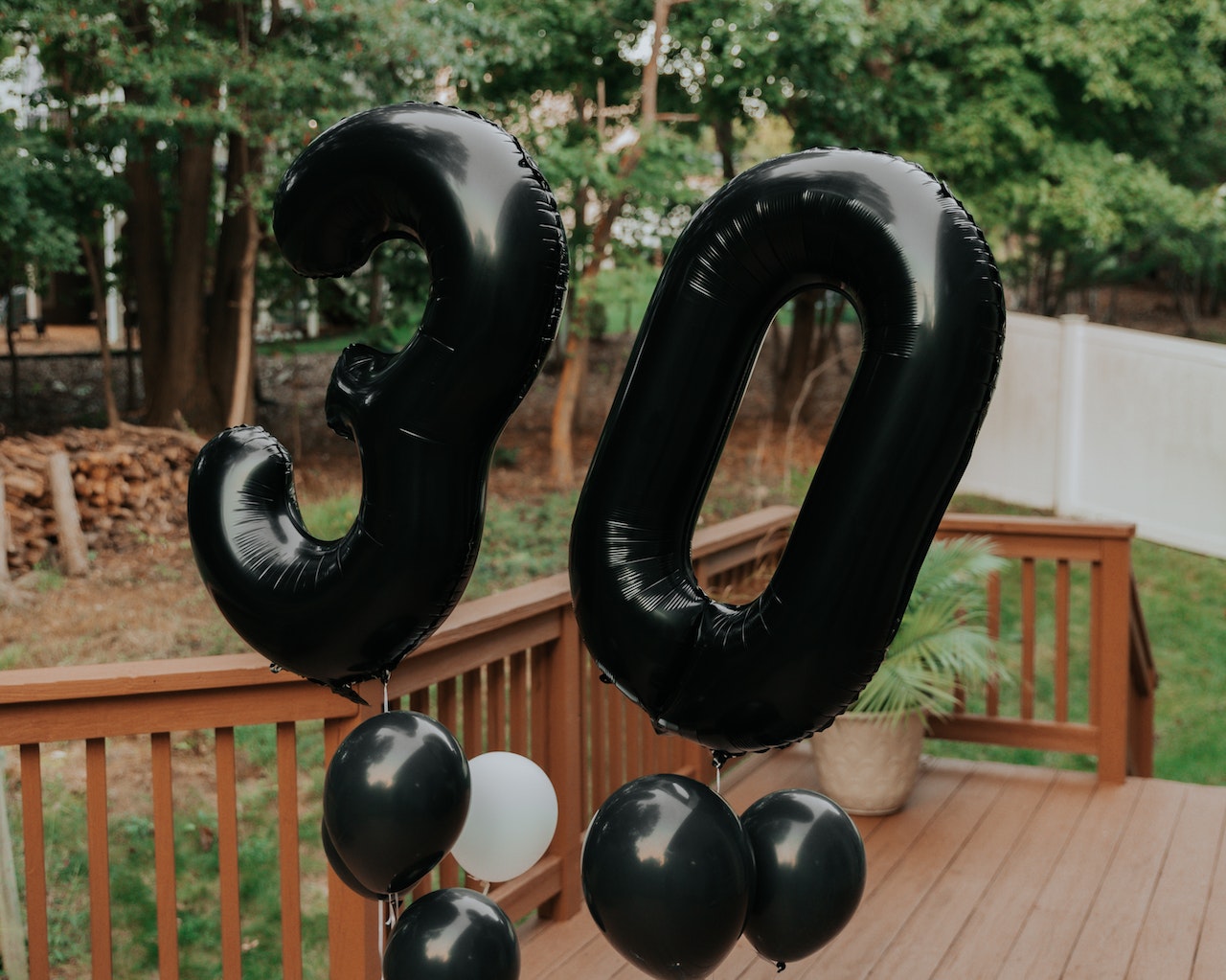 Na tym radosnym obrazku widoczne są balony z okazji 30. urodzin. Są one w różnych kształtach i kolorach, a cyfra "30" widnieje na kilku z nich, podkreślając tę wyjątkową rocznicę. Balony dodają koloru i radości do dekoracji, tworząc wspaniałą atmosferę świętowania